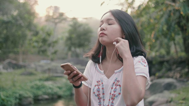 年轻的亚洲女人用耳机听音乐。视频素材