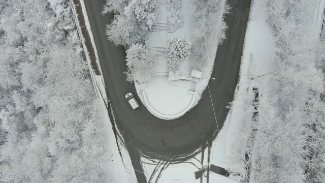 鸟瞰图转向公路在山区冬季积雪覆盖森林视频素材