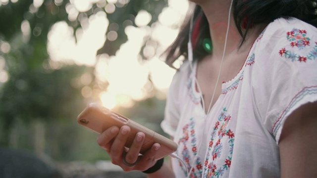 年轻女子在瀑布边听音乐。视频素材