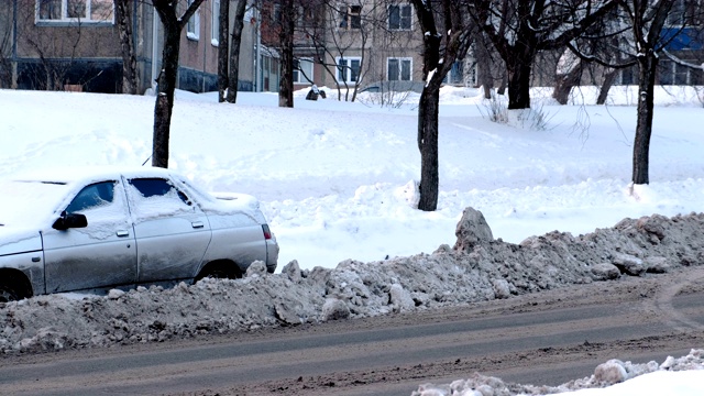 白雪覆盖的汽车停在积雪的路边。侧视图。视频素材