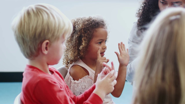 幼儿在课堂上举手，跟女老师学数数，侧视视频素材