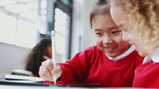 两个幼小的女学生在课堂上用平板电脑和手写笔画画视频素材