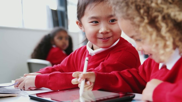 两个幼小的女学生在课堂上用平板电脑和手写笔画画视频素材