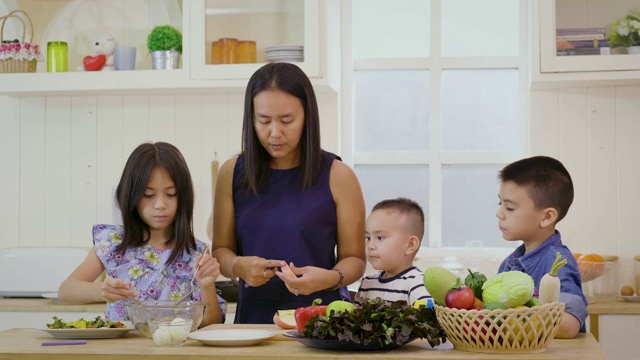 母亲和孩子在厨房里一起准备蔬菜和沙拉，快乐的家庭理念视频素材