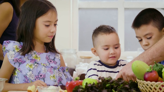 孩子们喜欢在家里的厨房里吃苹果，快乐的家庭观念视频素材