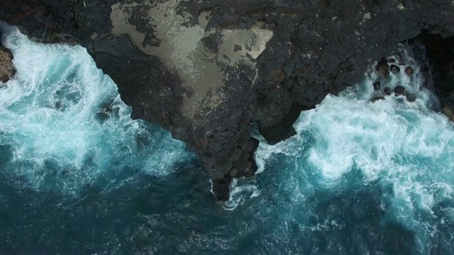 航拍:岩石海岸与来自蓝色海洋的汹涌海浪视频素材