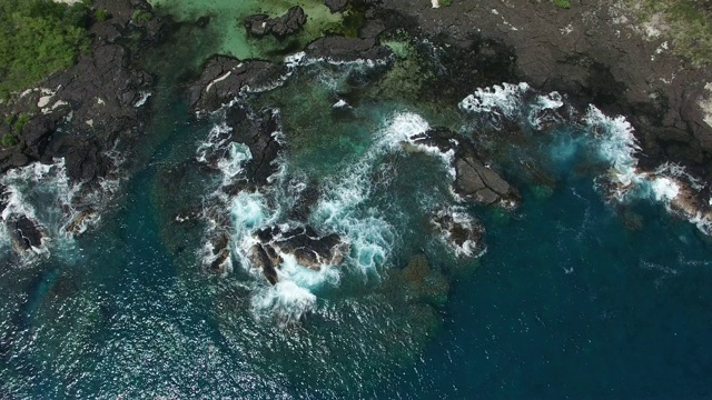 天线:蓝色的海洋，白色的海浪拍打着岩石海岸视频素材