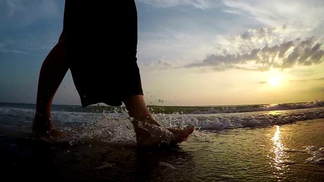 慢动作镜头的女人走在沙滩与海浪出来和日落视频素材