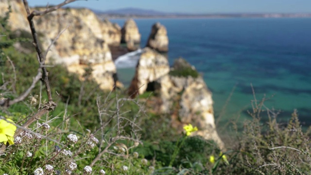 蓬塔·达·皮达德，葡萄牙南部著名的地方，拉各斯市，岩石海岸，大西洋的波浪，尖锐的岩石，蔚蓝的水，黄色的花，拱门，没有人，野生的海滩视频素材