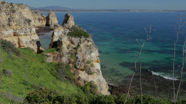 蓬塔·达·皮达德，葡萄牙南部著名的地方，拉各斯市，岩石海岸，大西洋的波浪，尖锐的岩石，蔚蓝的水，黄色的花，拱门，没有人，野生的海滩视频素材