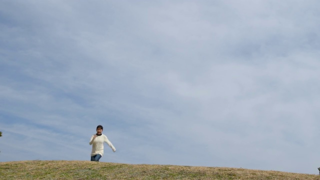 一个日本女孩在蓝天上奔跑跳跃视频素材