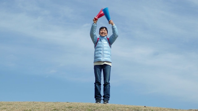 日本一名小学女生在蓝天上用扩音器欢呼视频素材