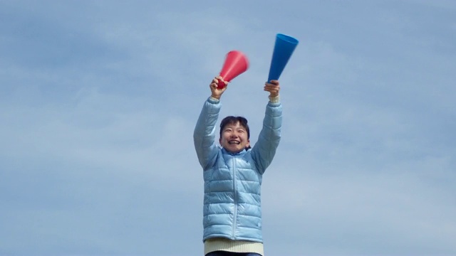 一个日本女孩在蓝天上用扩音器欢呼视频素材