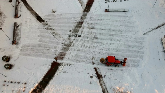 红色拖拉机清理城市广场，空中积雪视频素材