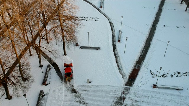 红色的旧拖拉机正在清理城市广场上的积雪视频素材