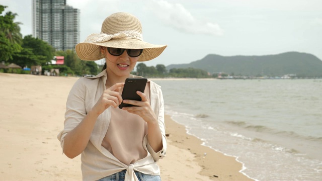 在海滩上玩智能手机的女人视频素材