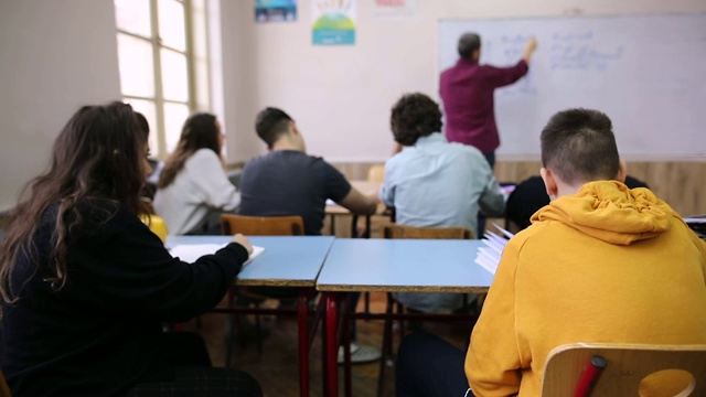 女生在桌子底下把纸传给同学视频素材