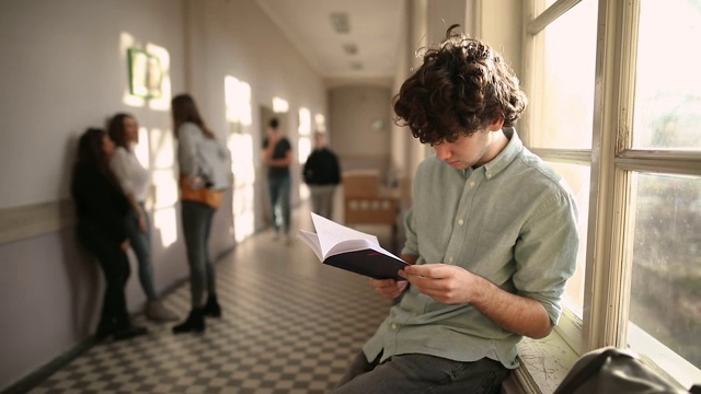 男生在学校走廊欺负同学，而女生则在一旁观看视频素材