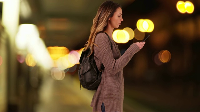 千禧一代的白人女孩晚上在城市街道上接听手机短信视频素材