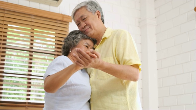 亚洲老夫妇喜欢在家里的客厅跳舞。居家养老的概念。视频素材