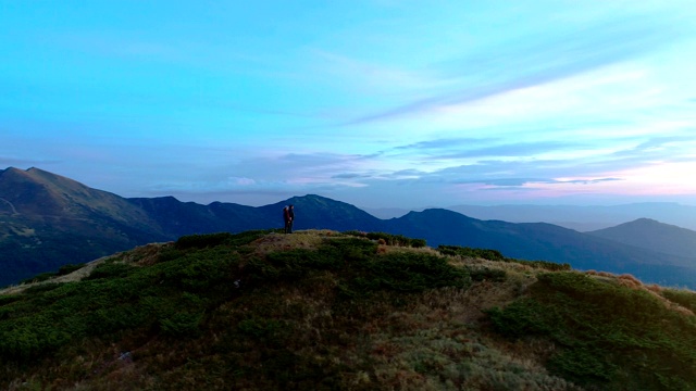 在日出的背景下，这对夫妇站在风景如画的山上视频素材