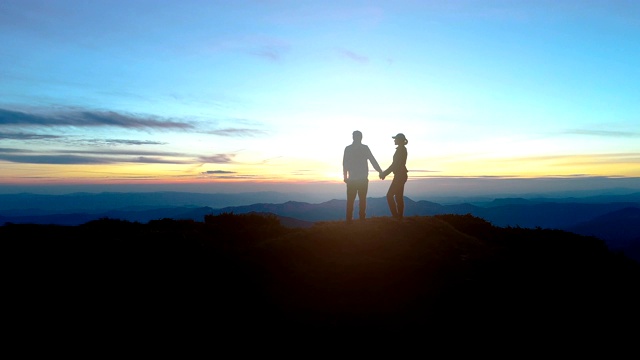 这对夫妇站在夕阳下的晚山上视频素材