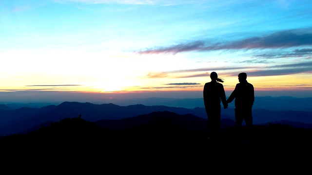 这对情侣站在夕阳背景下的晚山上视频素材