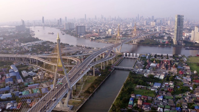 无人机镜头鸟瞰图，普密蓬悬索桥横跨曼谷市湄南河，在日落天空和云彩在桥上的汽车在泰国曼谷。视频素材