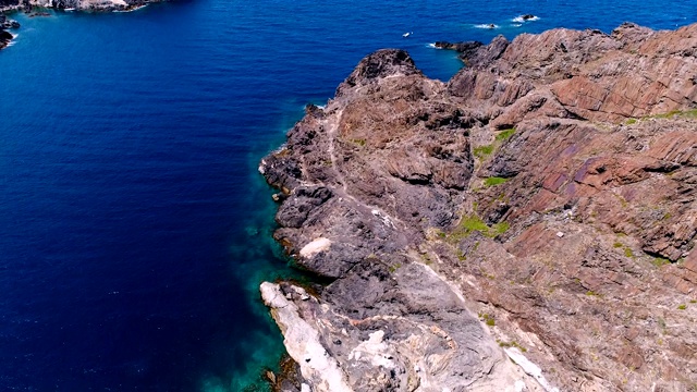 鸟瞰图上的一艘船在Cap De Creus海湾在西班牙。美丽的风景岩石和清澈的地中海绿松石水。视频素材