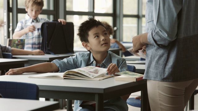 微笑的男孩听着年轻的女老师视频素材