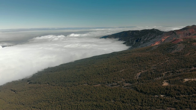 空中射击。全景高山森林在云层的水平。在火山密布的加那利群岛，地面是红色的视频素材