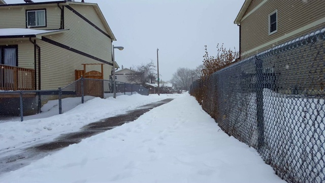 冬季下雪时住宅间的人行道。郊区城市的雪边人行道。视频素材