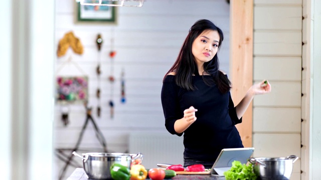 快乐的亚洲女人有乐趣和舞蹈在厨房烹饪新鲜的有机膳食视频素材