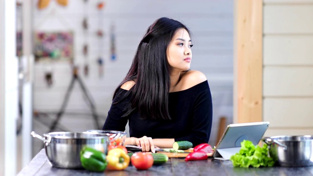 疲惫时髦的年轻亚洲女人正在煮新鲜的饭菜中有头痛视频素材