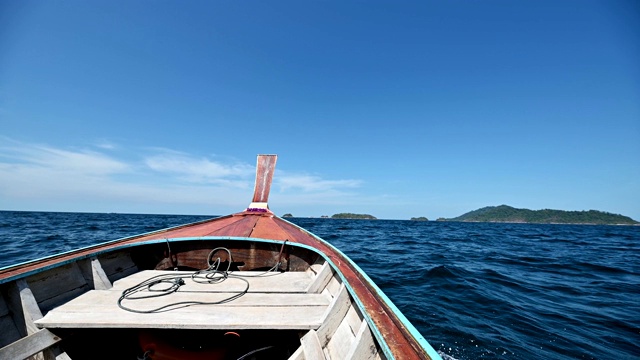 长尾木船航行在蓝色的海面上到岛屿视频素材