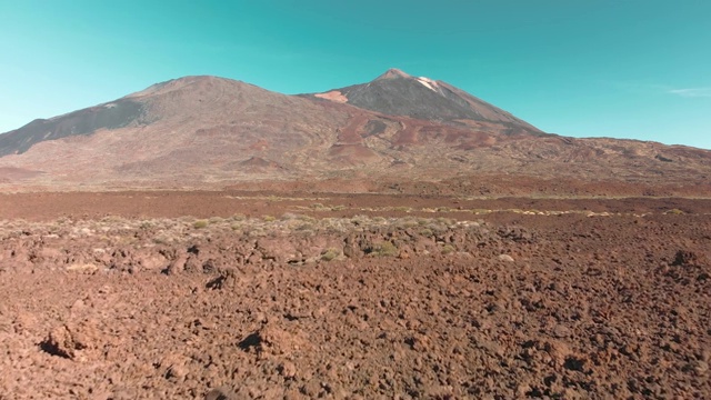 空中无人机拍摄。红色的沙漠火山景观。蓝色的天空映衬着石头和一座火山山。殖民和迁移到火星和其他星球的概念。低跨度的石谷。向前移动视频素材