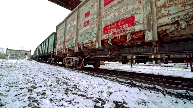 在被雪覆盖的地面上，一排排五颜六色的集装箱沿着火车站和车站的铁轨行驶。视频素材