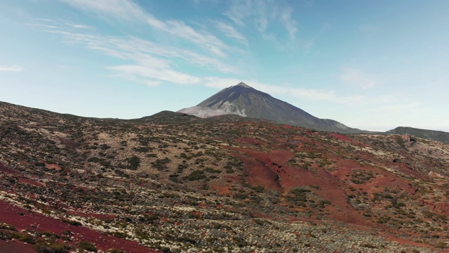 空中射击。在一个阳光明媚的日子里，泰德火山的顶峰在一个火山山谷里。在前景有一个红色的火山土壤和不寻常的手工植被，飞行到其他星球的概念和殖民火星。泰德视频素材