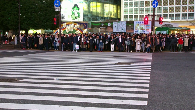 在日本东京涩谷的夜晚，一条繁忙的街道显示了繁忙的车流和行人视频素材