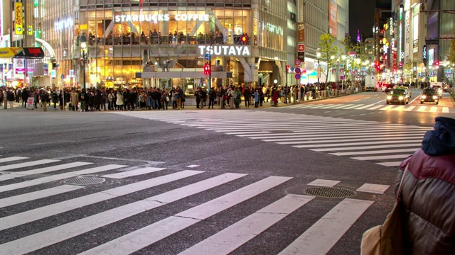 在日本东京涩谷的夜晚，一条繁忙的街道显示了繁忙的车流和行人视频素材