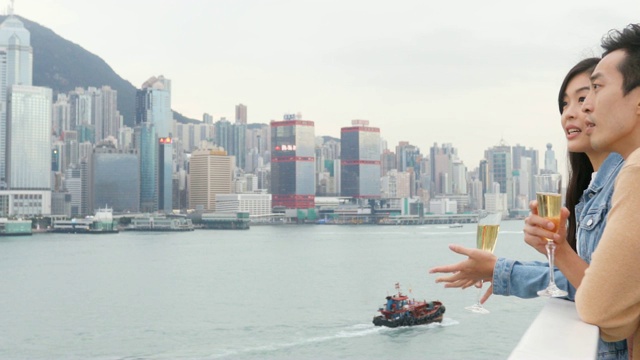 快乐的亚洲夫妇与香槟酒和香港天际线庆祝视频素材