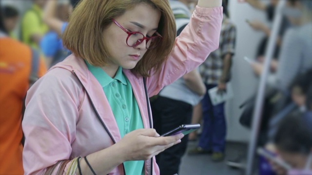 年轻女子在乘坐地铁时使用智能手机，慢镜头视频素材