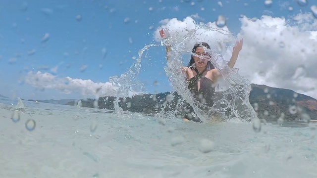 夏天亚洲女人有乐趣溅水和放松在海滩上超级慢动作视频素材