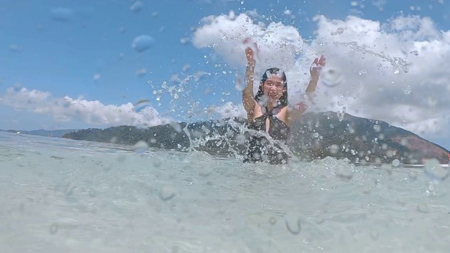 夏天亚洲女人有乐趣溅水和放松在海滩上超级慢动作视频素材