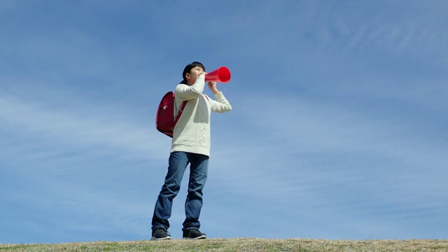 日本一名小学女生在蓝天上用扩音器欢呼视频素材