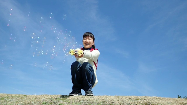 一名日本小学生在蓝色的天空中玩肥皂泡视频下载