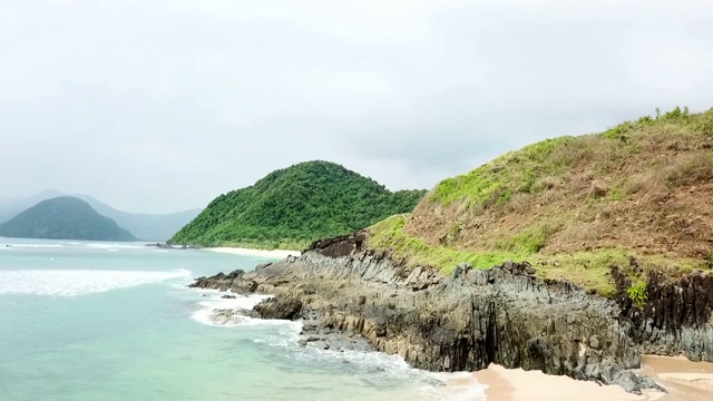 海浪轻轻拍打着岩石，草山沿海岸线在龙目岛，巴厘岛视频素材