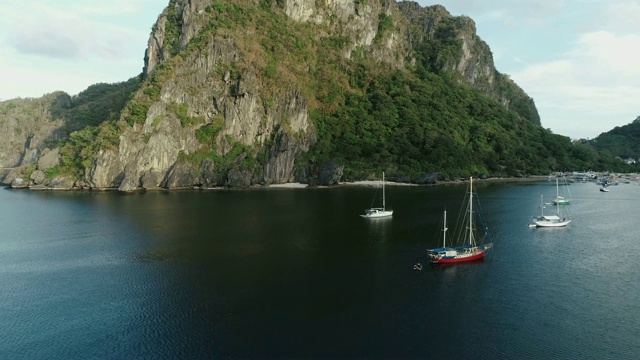 无人机拍摄的是覆盖着热带森林的高山和停泊在海湾中的船只。热带景观。旅游概念菲律宾，厄尔尼诺。视频素材