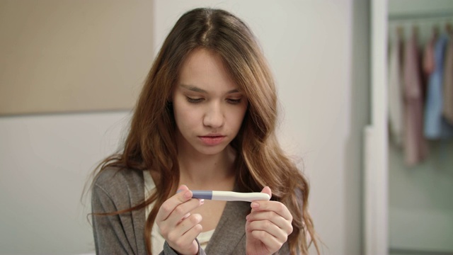 焦急等待怀孕检测结果的妇女。女孩在看验孕棒视频素材