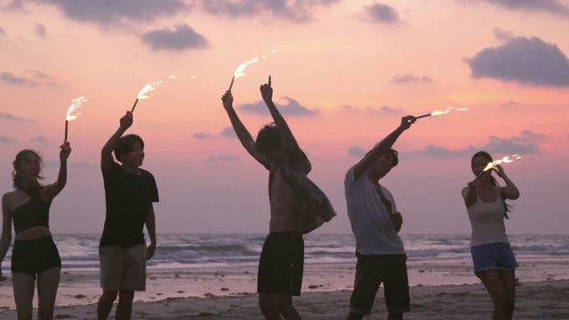 在夕阳的背景下，一群朋友在一起欢畅地放烟花。视频素材